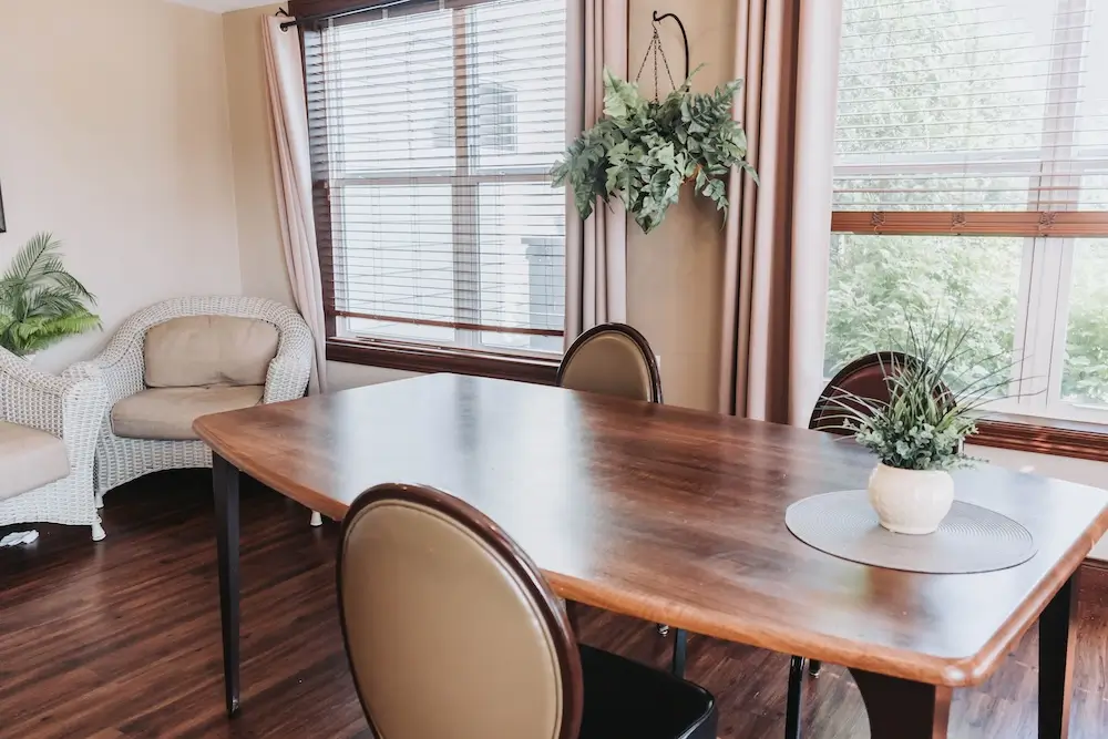 Wooden dining table by bright windows at Oakwood Senior Living