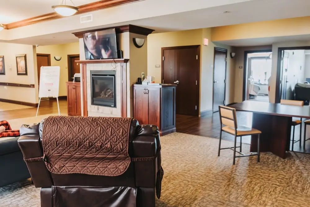 Lounge with leather armchairs and a fireplace at Oakwood Senior Living