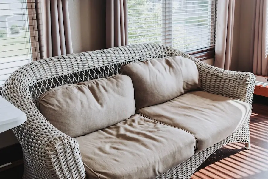 Wicker loveseat in the sunlit sunroom at Oakwood Senior Living