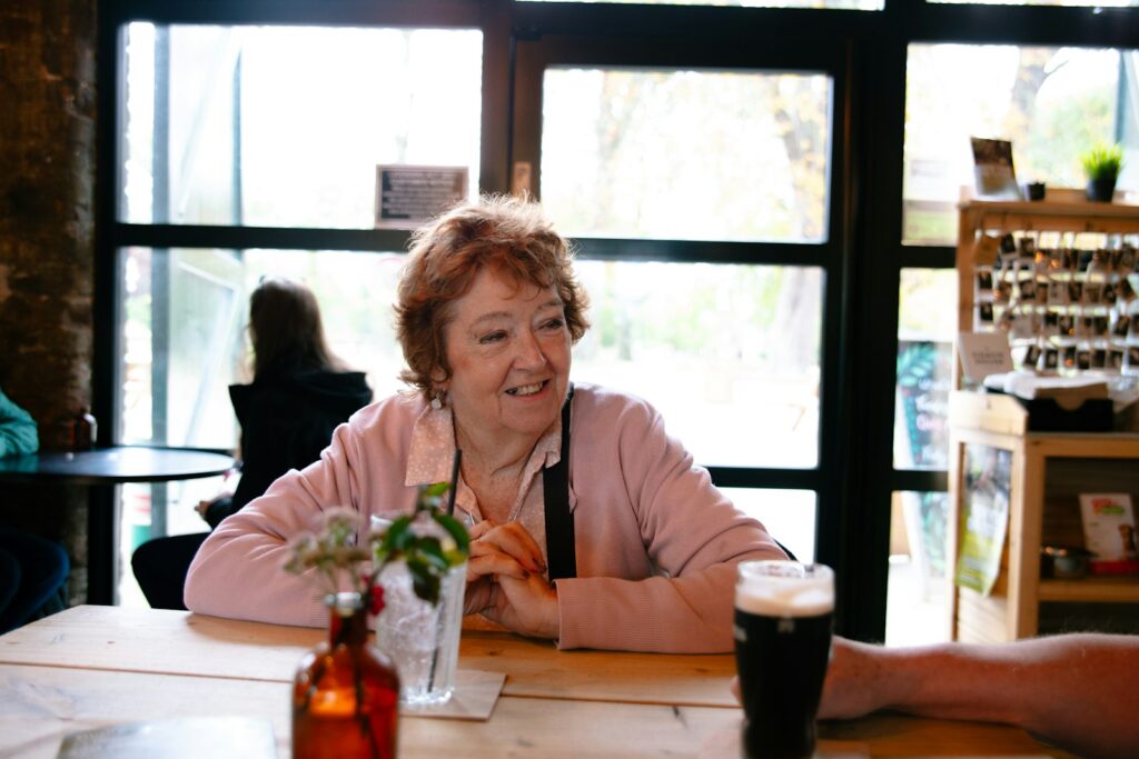 An older woman smiling at a table by a window
