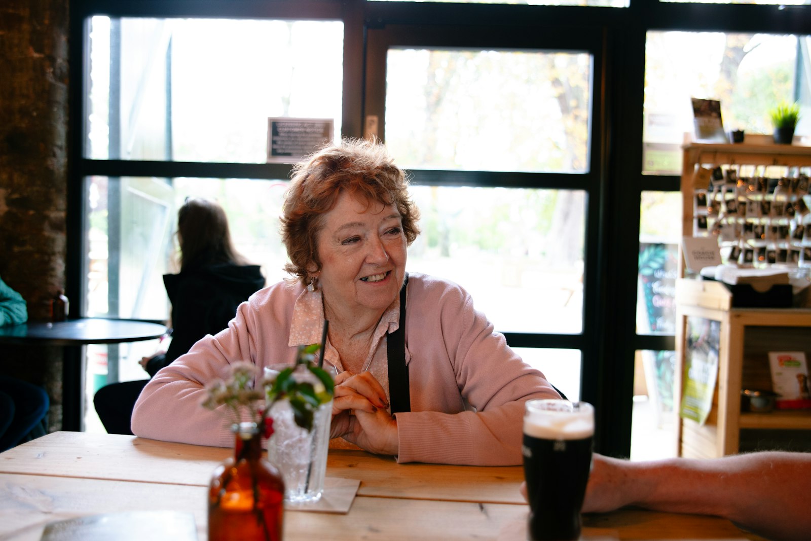 An older woman smiling at a table by a window