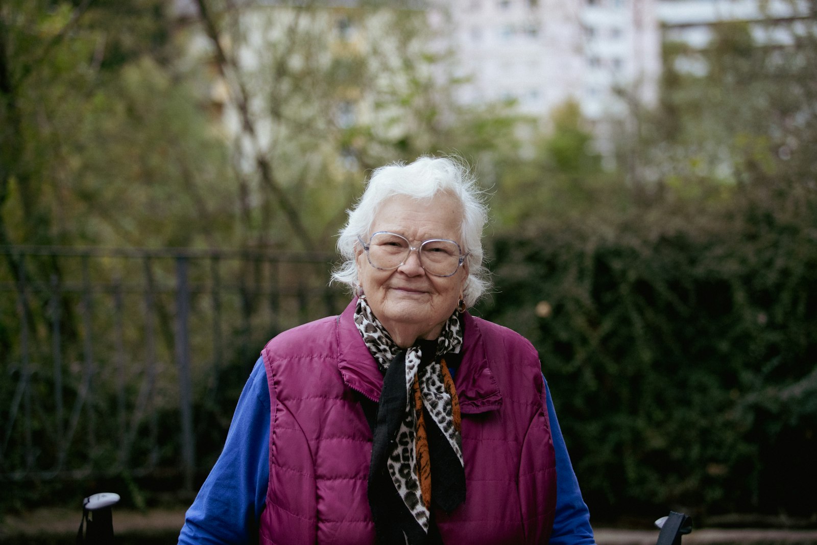 An older woman in a warm vest sitting outdoors